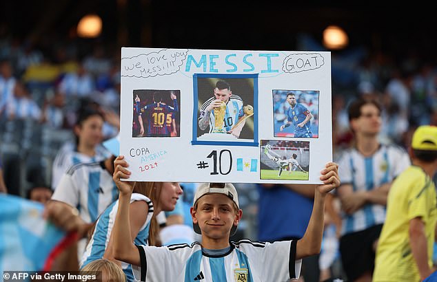 A young Argentina fan holds a Lionel Messi sign ahead of the Conmebol 2024 Copa America tournament group A football match between Chile and Argentina