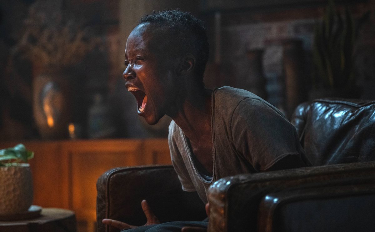 Sam (Lupita Nyong'o) sits in a large leather armchair in a dark room, closes her eyes and screams in Michael Sarnoski's A Quiet Place: Day One