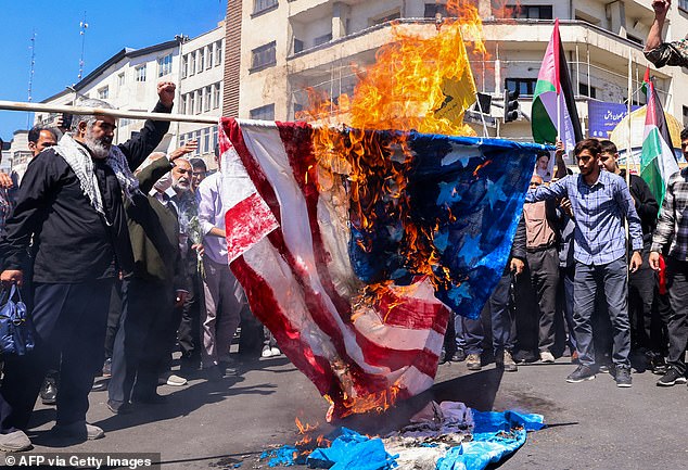 Protesters burn an American and an Israeli flag during the funeral of seven members of the Islamic Revolutionary Guard Corps who were killed in an attack in Syria