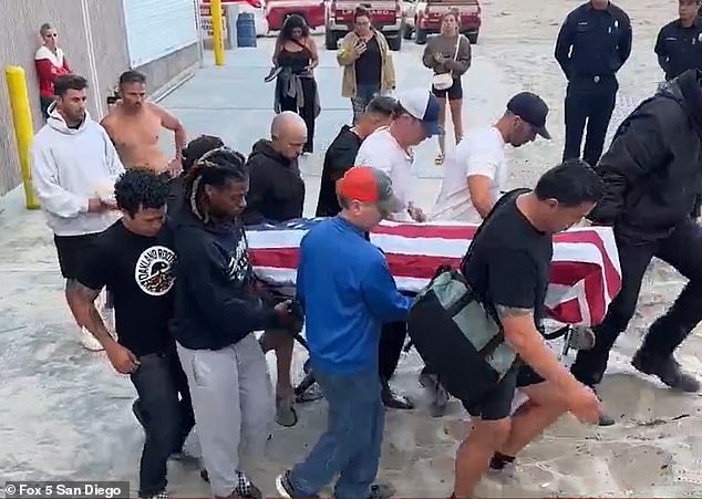 The young man's body was seen with an American flag draped over it as local police and firefighters took him to the medical examiner's van.