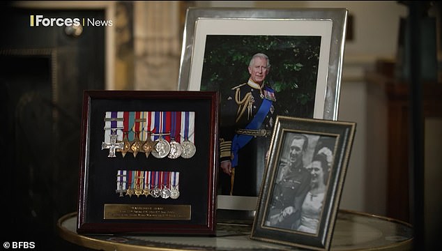 Also on the table next to the Queen is a photograph of her husband the King, taken in the garden of Clarence House, where he wears his Royal Navy uniform as Admiral of the Fleet.