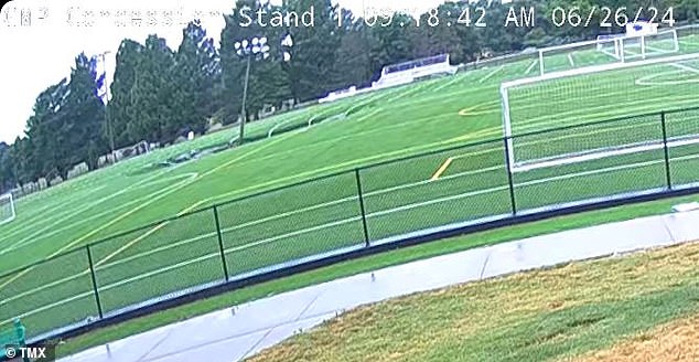 The shocking moment the sinkhole formed in an Illinois football field was captured on a security camera - swallowing a set of floodlights