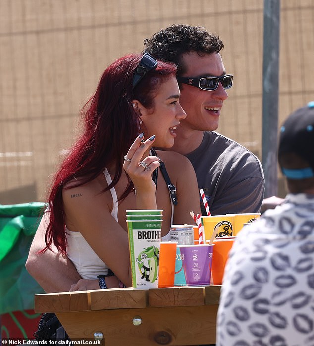 The couple chatted and mingled with friends as they sat on a beach at the festival