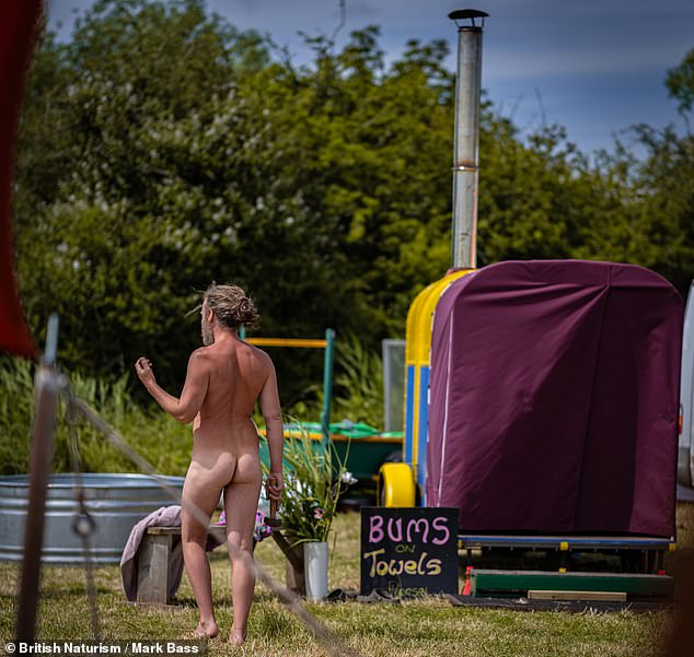 A visitor to Nudefest walks past a sign that reads 'buttocks on towels'