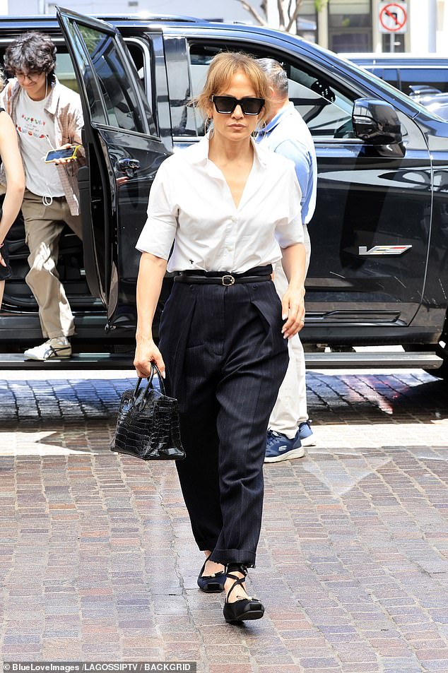 The former star of Maid in Manhattan wore a tight white Oxford shirt with rolled-up sleeves and black pants, but kept a low profile behind dark designer sunglasses