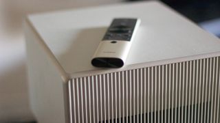 a white square projector with a remote control on it