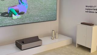 Samsung The Premiere 8K projects a football match, with its wireless connection box on a separate device