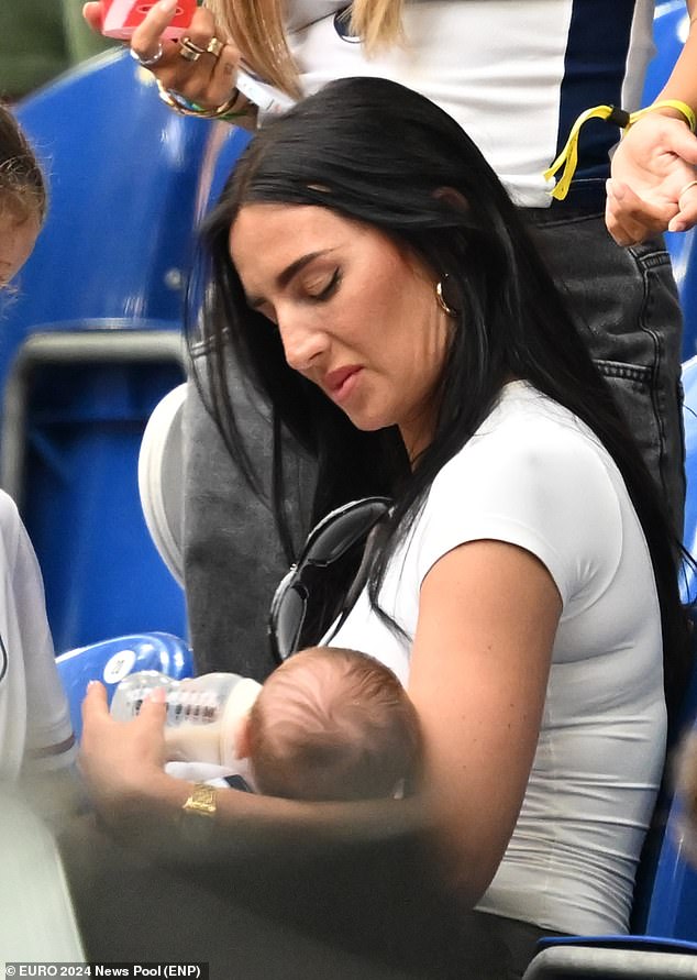 The WAG was photographed feeding her baby son after taking her place in the stands for the match