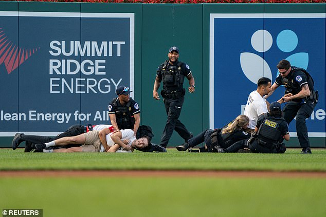 Police officers attempt to arrest protesters who had stormed the field during the charity game