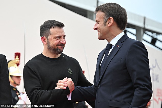 Ukrainian President Volodymyr Zelensky and French President Emmanuel Macron join hands upon arrival at the ceremony.  France said this week it will send Mirage fighter jets to Kiev