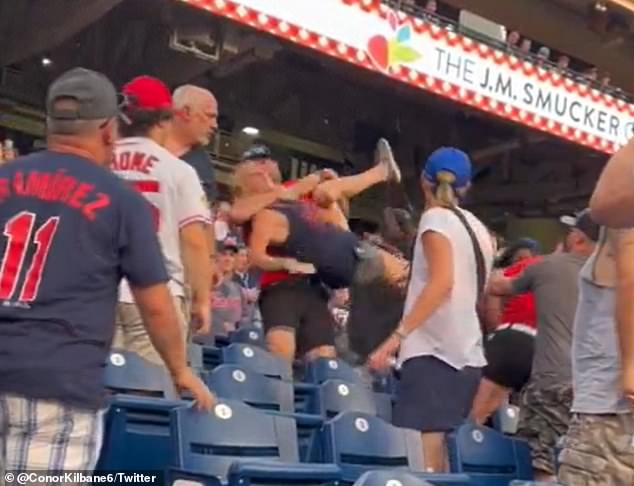 A female fan is lifted away after exchanging punches with another woman in the stands