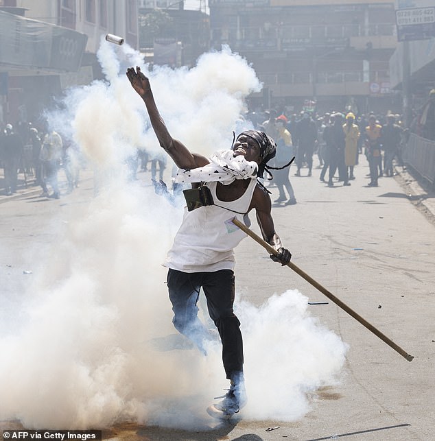 A demonstrator throws a tear gas canister back at police during a strike to protest tax increases in Kenya