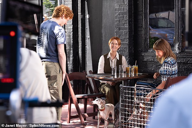 Dolly bends over to pet an adorable gray dog ​​that has run towards them when Miranda's son Brady, played by Niall Cunningham, walks up to them