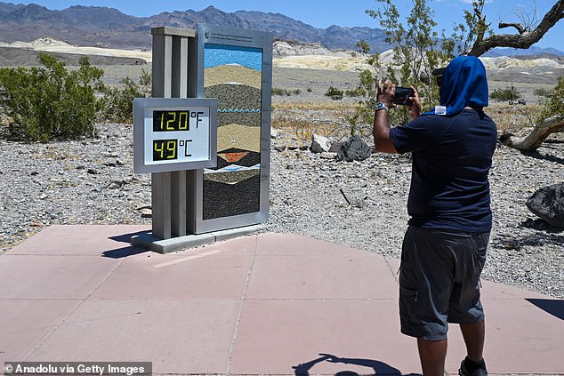 A man takes a photo of a thermometer reading 120 Fahrenheit at the Furnace Creek Visitor Center in Death Valley
