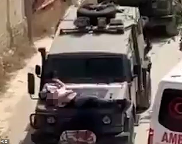 An injured Palestinian man was filmed Saturday tied to the hood of an IDF vehicle during an arrest raid in the West Bank city of Jenin.