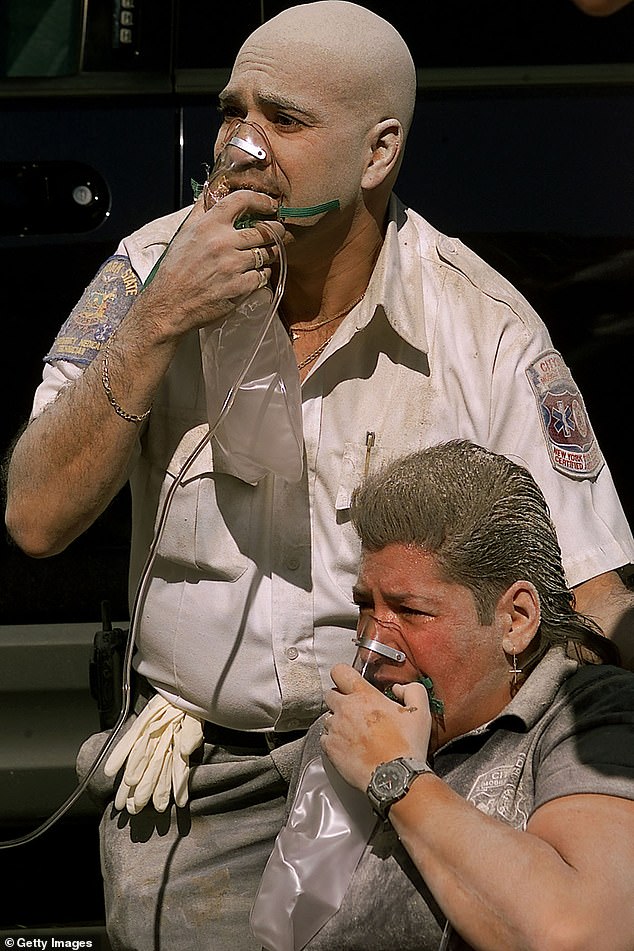 A paramedic and a police officer breathe oxygen after the South Tower of the World Trade Center collapsed
