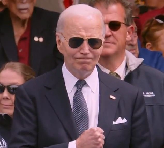 An emotional President Joe Biden clenches his fist at the end of his speech on the 80th anniversary of D-Day during the 'missing man' flyover in Normandy