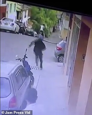 Seconds after entering the second door, the masked attacker runs into the street towards the getaway bike