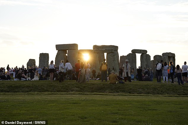 Revelers enjoy the summer solstice celebration at Stonehenge as the sun sets beneath the stones