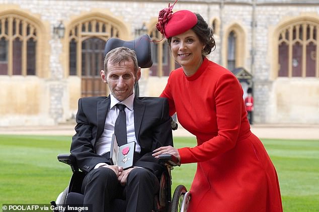 Former rugby league player Rob Burrow and his wife Lindsey pose for a photo with his medal after receiving his MBE at Windsor Castle in 2022