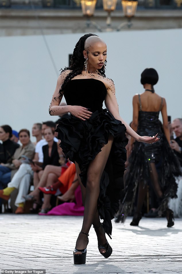 FKA Twigs made sure all eyes were on her as she hit the runway in a strapless black ruffled dress by Chanel, which she paired with sheer tights and sky-high platform heels.
