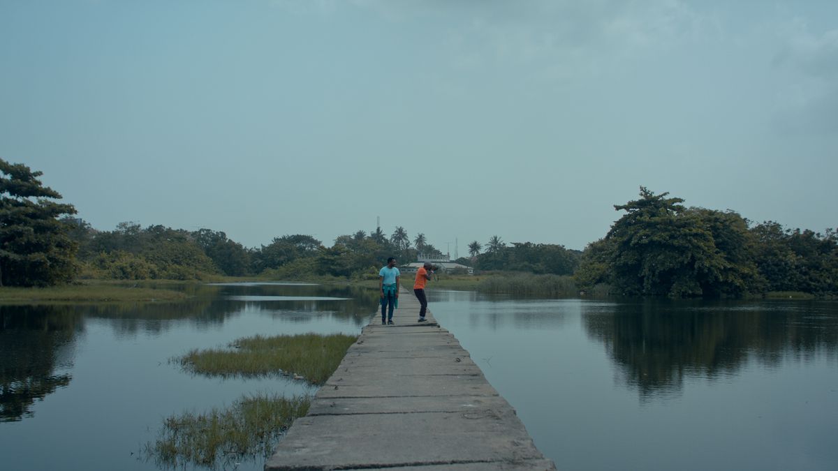 Two boys stand on a bridge and look at the water in All the Colors of the World are Between Black and White