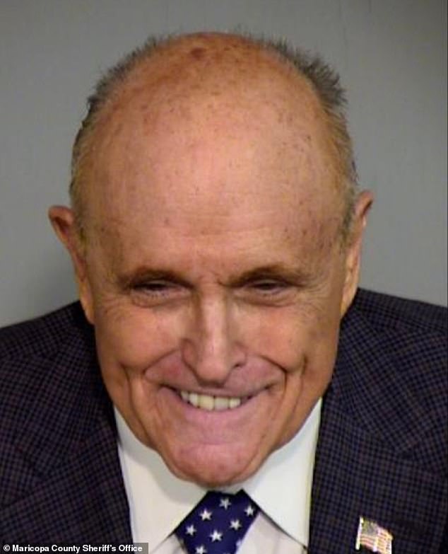 Rudy Giuliani grins and looks down at the camera in his mugshot in the Arizona 'fake voters' case