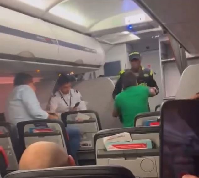 A passenger intervenes and tries to stop Officer Carlos Quiñones from taking his brother off an Avianca flight for punching a law enforcement officer in the face