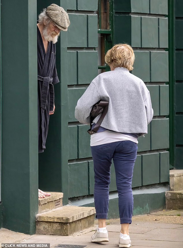 Sir Ian McKellen greets a friend who gives him a card outside his London home yesterday