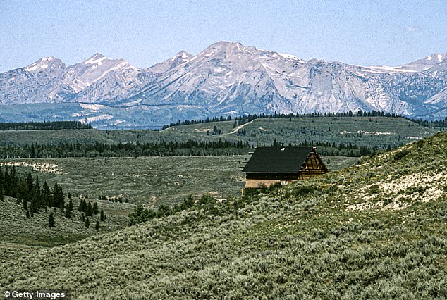 View of a log cabin on a hill, overlooking the Hoback Basin and mountain views of the Wind River Range, Bondurant, Wyoming