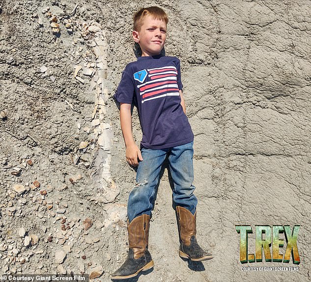 The three boys were walking in the Hell Creek formation when they saw what looked like a large white petrified bone in the ground.  In this photo, Liam Fisher lies next to an exposed part of the fossil