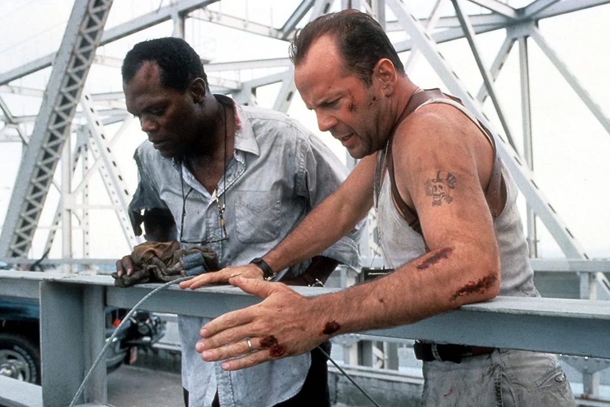Two disheveled men look over the railing of a metal bridge in Die Hard with a Vengeance.