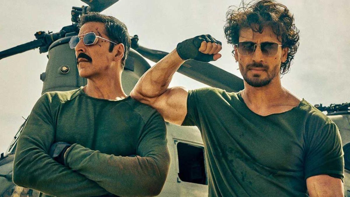 Tiger Shroff flexes his biceps, resting on Akshay Kumar's shoulder, in front of a helicopter in Bade Miyan Chote Miyan.  Kumar crosses his arms.