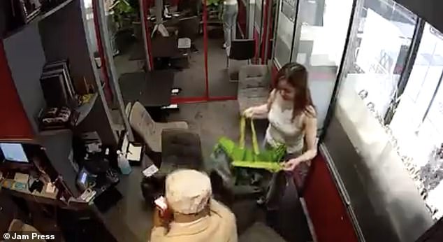 The robber orders the store clerk to help him search the store and gives her a plastic bag that they then fill with items