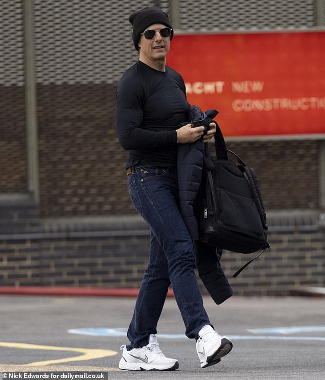 Tom Cruise, 61, looked pale in a tight black top on Tuesday as he landed at London Heliport in Battersea to continue filming Mission Impossible 8