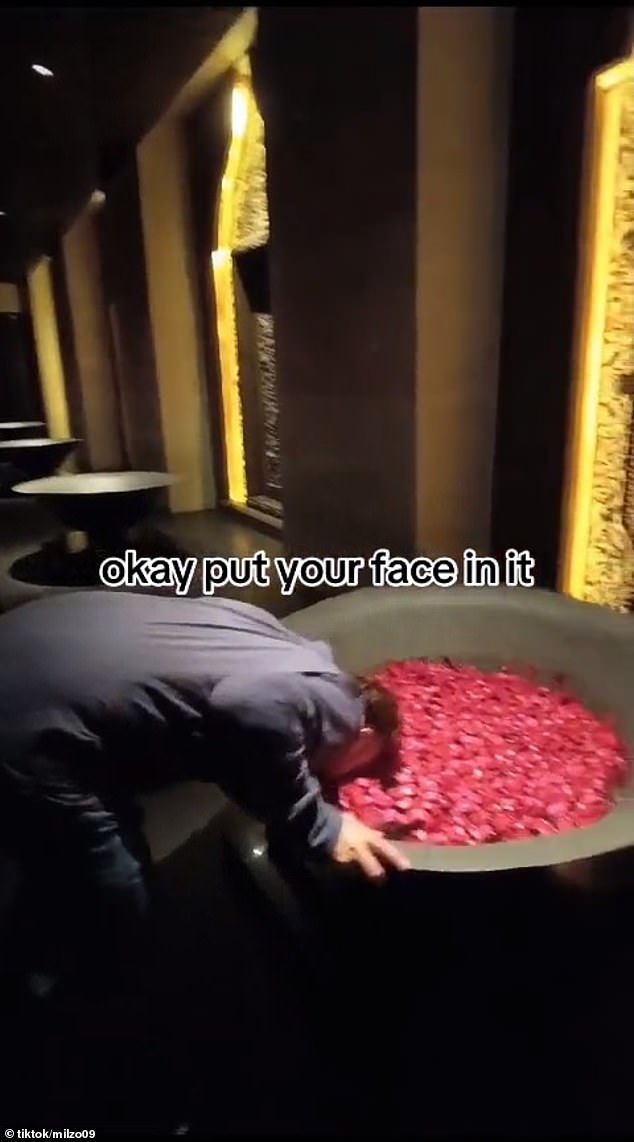 A well-dressed tourist in Bali has caused a stir after he knocked over a bowl of water and flower petals in a hotel while trying to submerge his head in it (pictured)