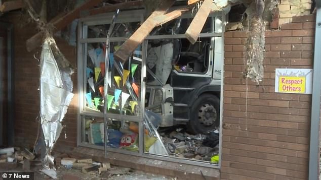Emergency services attempted to free a trapped male truck driver after he crashed into a classroom at St Joseph's Catholic Primary School in Moorebank (pictured)