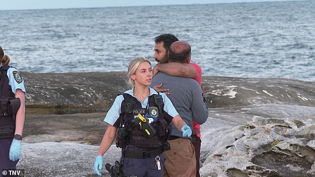 Bystanders comfort each other after three women were swept into the water at Cape Solander