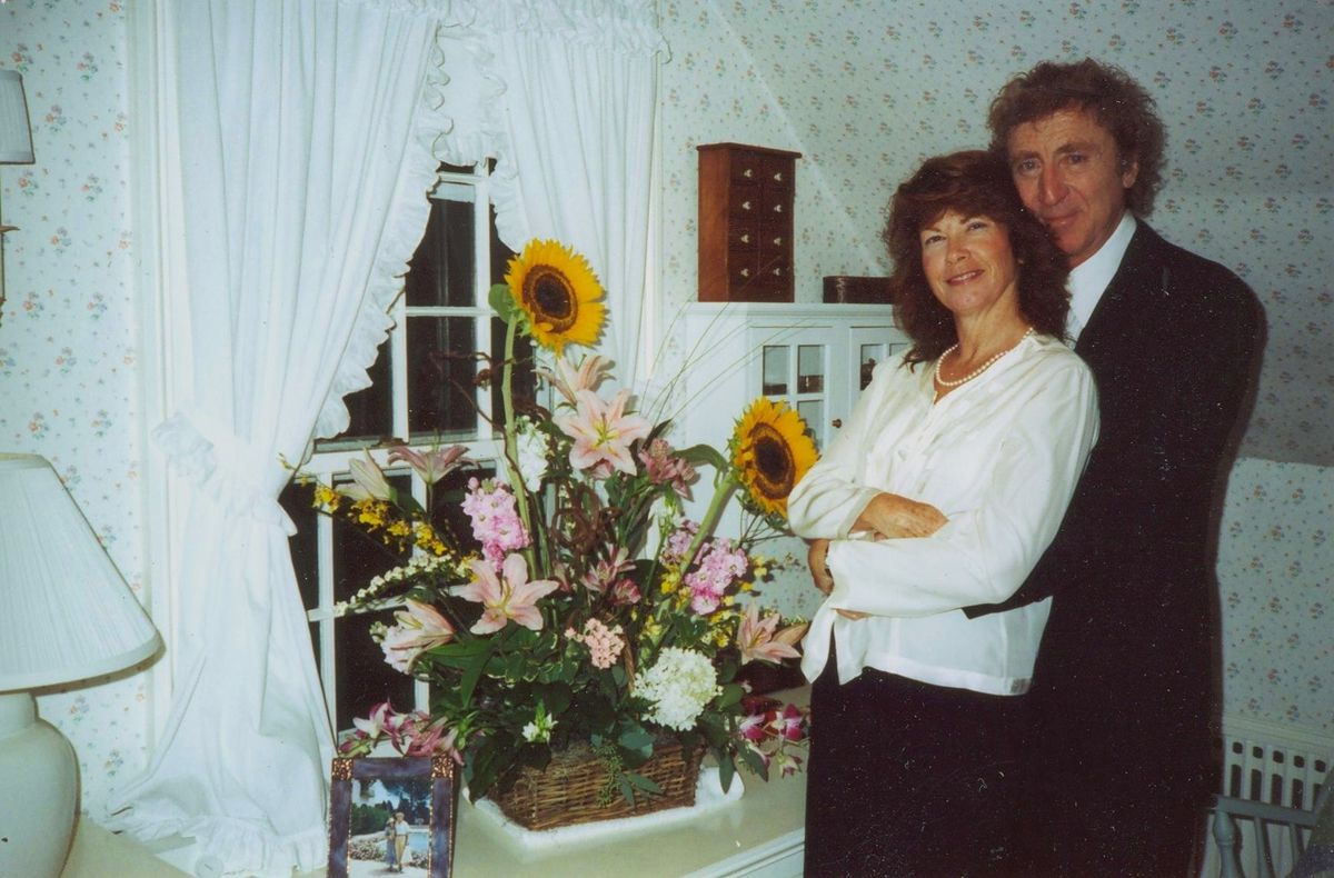 File photo of Gene Wilder standing in a room with a woman next to a large bouquet of flowers in Remembering Gene Wilder.