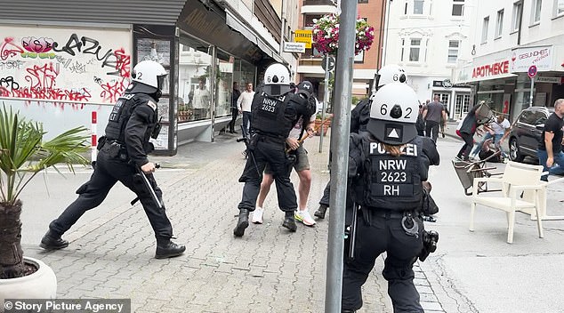 German police officers struggle with a fan after violence broke out ahead of a match between the Three Lions and Serbia
