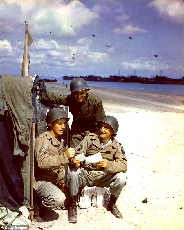 US soldiers Sergeant RA Forbis, Private John Krisa and Corporal VE Holtz of the Army Corps of Engineers read letters on an unknown beach captured on D-Day