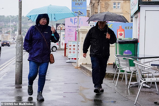 Britain has been battered by cold winds and rain so far in June, with temperatures half as high as a year ago, the Met Office said.  Pictured: People holding umbrellas during a downpour in Western-super-Mare on June 13