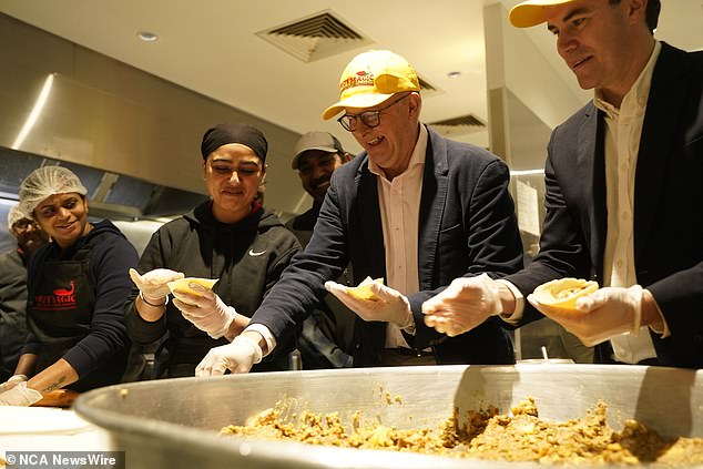 Prime Minister Anthony Albanese (pictured centre) has been criticised for promoting government tax cuts while visiting an Indian sweet shop in Melbourne on Sunday