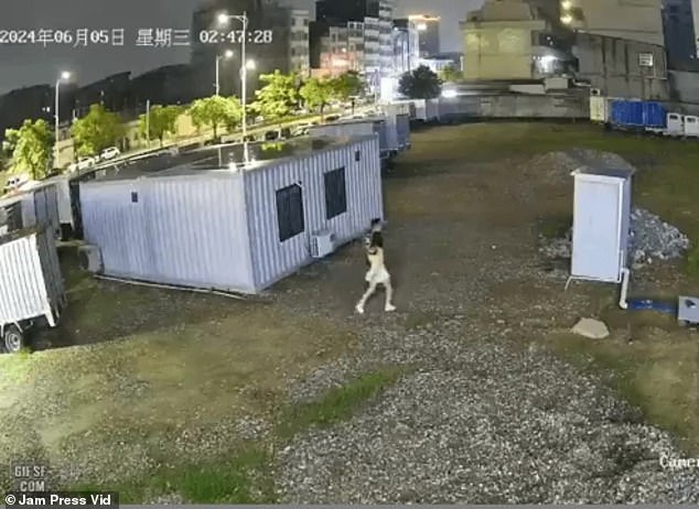 A couple is seen walking through what appears to be a construction site toward a portable toilet