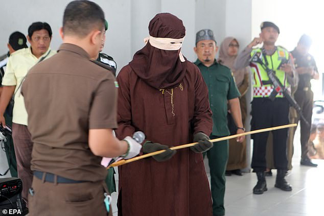 Photos show an intimidating executor, an 'algojo', holding a rattan before publicly beating four men in front of officials at an Islamic court.