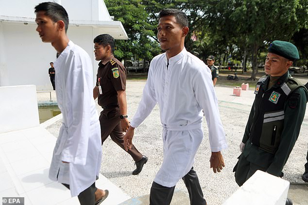 Two of the men are seen wearing white tunics as they arrive at the building in Banda Aceh where they were belatedly beaten for violating the region's Sharia law on consuming alcohol.