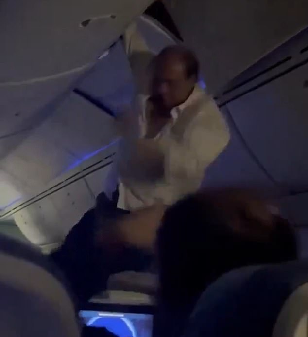 A male passenger is helped from the overhead bin after being thrown from his seat following turbulence on an Air Europa flight from Spain to Uruguay