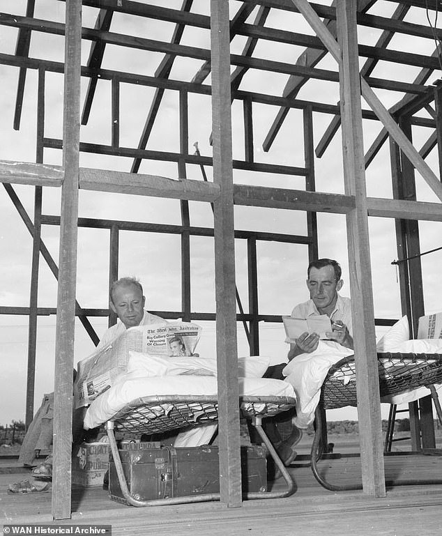 The photo shows men sitting in fold-out beds in an unfinished extension of the Pier Hotel in December 1959.