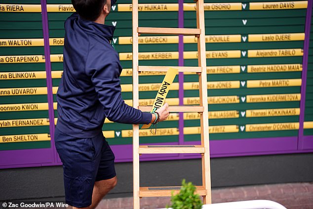 A ground staff member removes Andy Murray's name from a playing order board at Wimbledon today