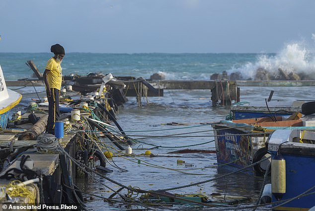 A fisherman looks out over vessels damaged by Hurricane Beryl at Bridgetown Fisheries in Barbados, Monday, July 1, 2024